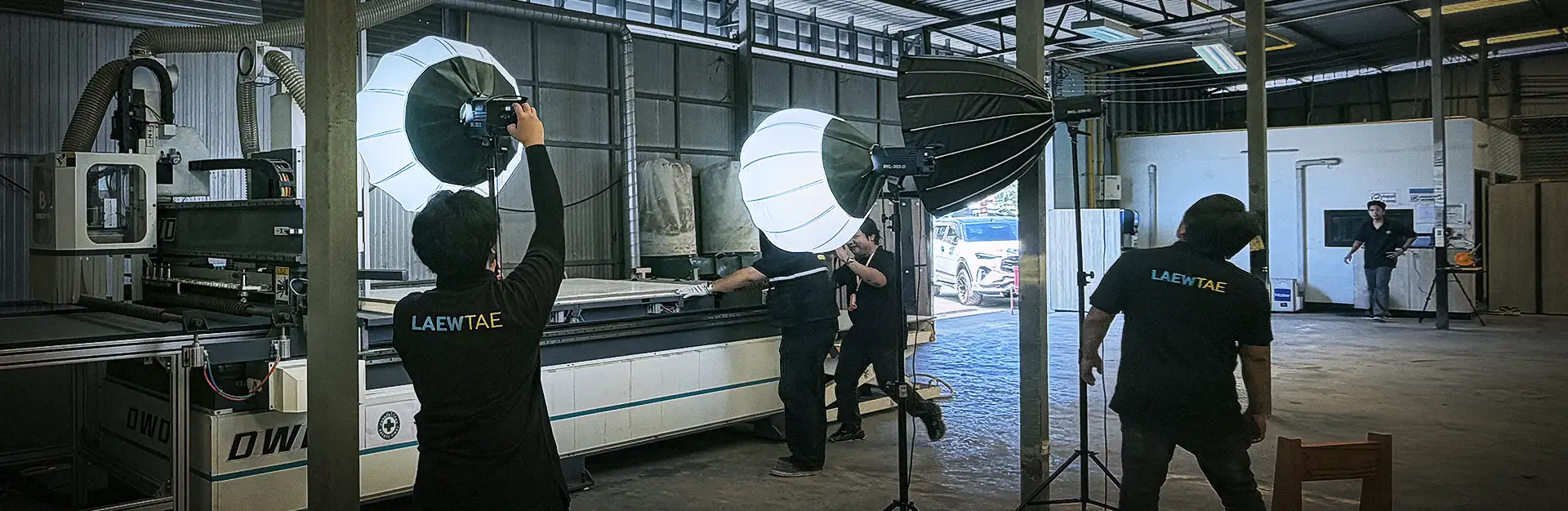 บรรยากาศการทำงานในคลังสินค้าไม้ของ Mela Deco ขณะทีมงานแล้วแต่บันทึกภาพมุมกว้าง